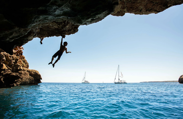 Climber with harness and rope on a Tramuntana limestone wall